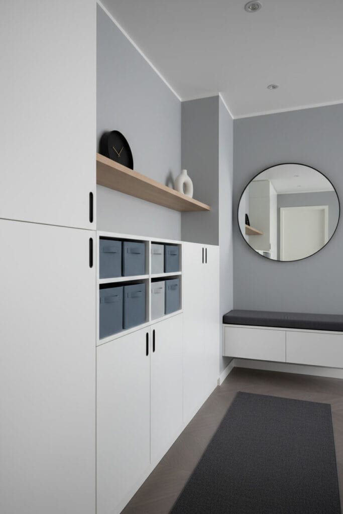 Couloir deco fonctionnel minimaliste avec rangement intégré blanc, banc mural, miroir noir et étagère flottante.