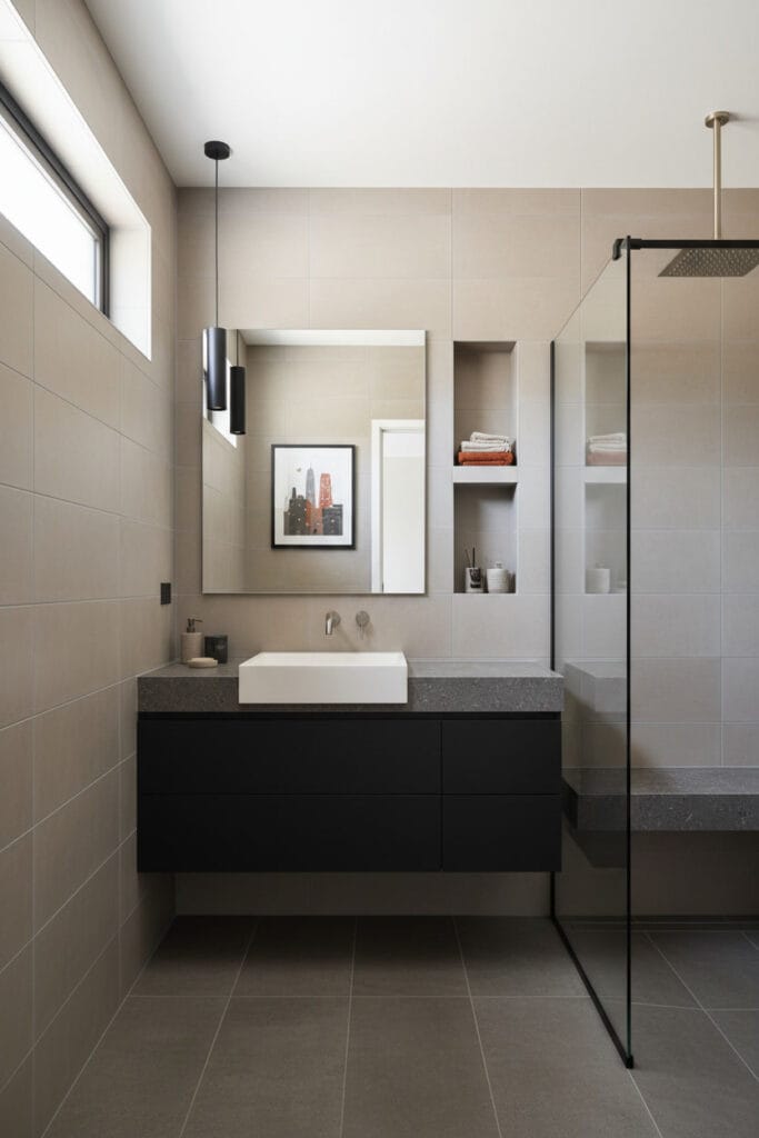 Salle de bain moderne industrielle mettant en valeur les matériaux adaptés à l'humidité : carrelage mat, pierre reconstituée et verre, pour une Deco Salle de Bain durable.