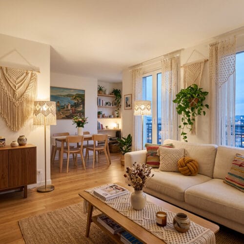 Salon ouvert sur salle à manger décoré en macramé bohème avec suspension, coussins et rideaux